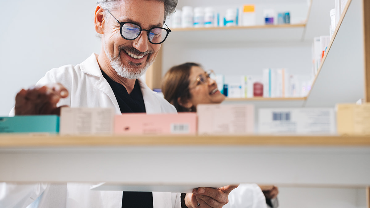 Male pharmacist picking prescription medication in a drug store